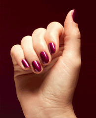 Hand showing short, rounded nails painted in Big Sagittarius Energy, a deep shimmery magenta OPI nail polish, catching the light against a rich burgundy background for a bold, glossy manicure look.