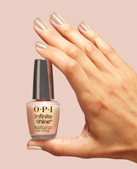Hand with pearly pink shimmer manicure holding OPI Infinite Shine MarshmelloOo So Sweet long-lasting nail polish bottle against a blush background, highlighting the glossy finish for an OPI nail polish gift set