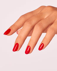 Hand with neatly manicured oval nails showcases Red Heads Ahead OPI nail polish, a glossy bright red nail lacquer, against a clean light pink background, highlighting the vibrant color and smooth, even coverage for salon-quality nails at home.