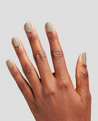 Hand with medium brown skin tone displaying neatly manicured nails painted in Suzi’s Pager, a taupe-beige OPI nail polish nail lacquer, against a clean light gray background for a modern, salon-quality look.
