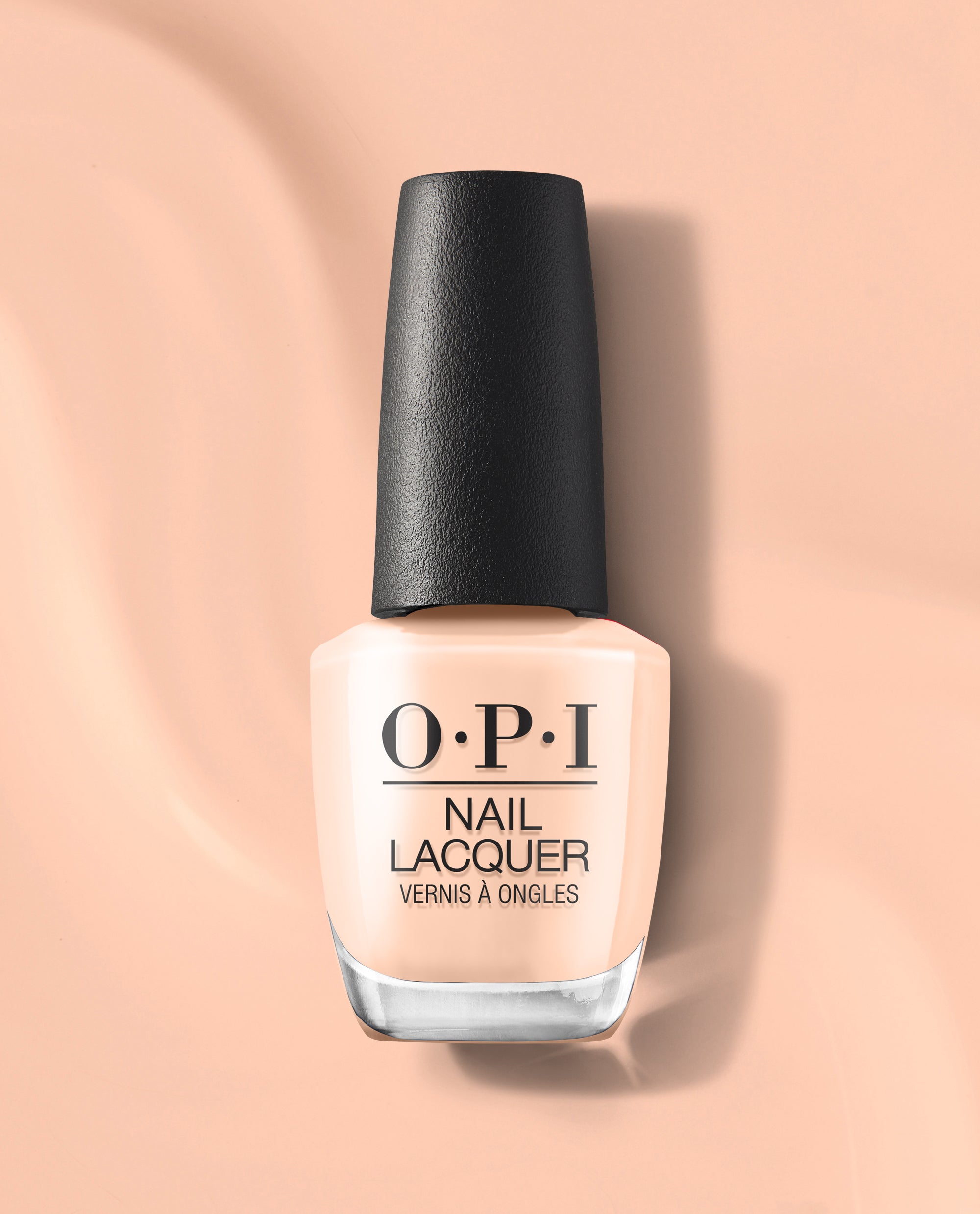 OPI Suzi Take a Vow nail lacquer bottle in a soft peachy nude shade stands upright with a black cap on a matching peach background, a subtle choice for fall nail colors.