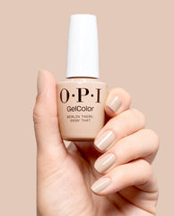 Hand holding OPI GelColor Berlin There, Doin’ That gel nail polish in a glossy beige-taupe shade, with matching manicured nails against a soft neutral background for fall nail colors.