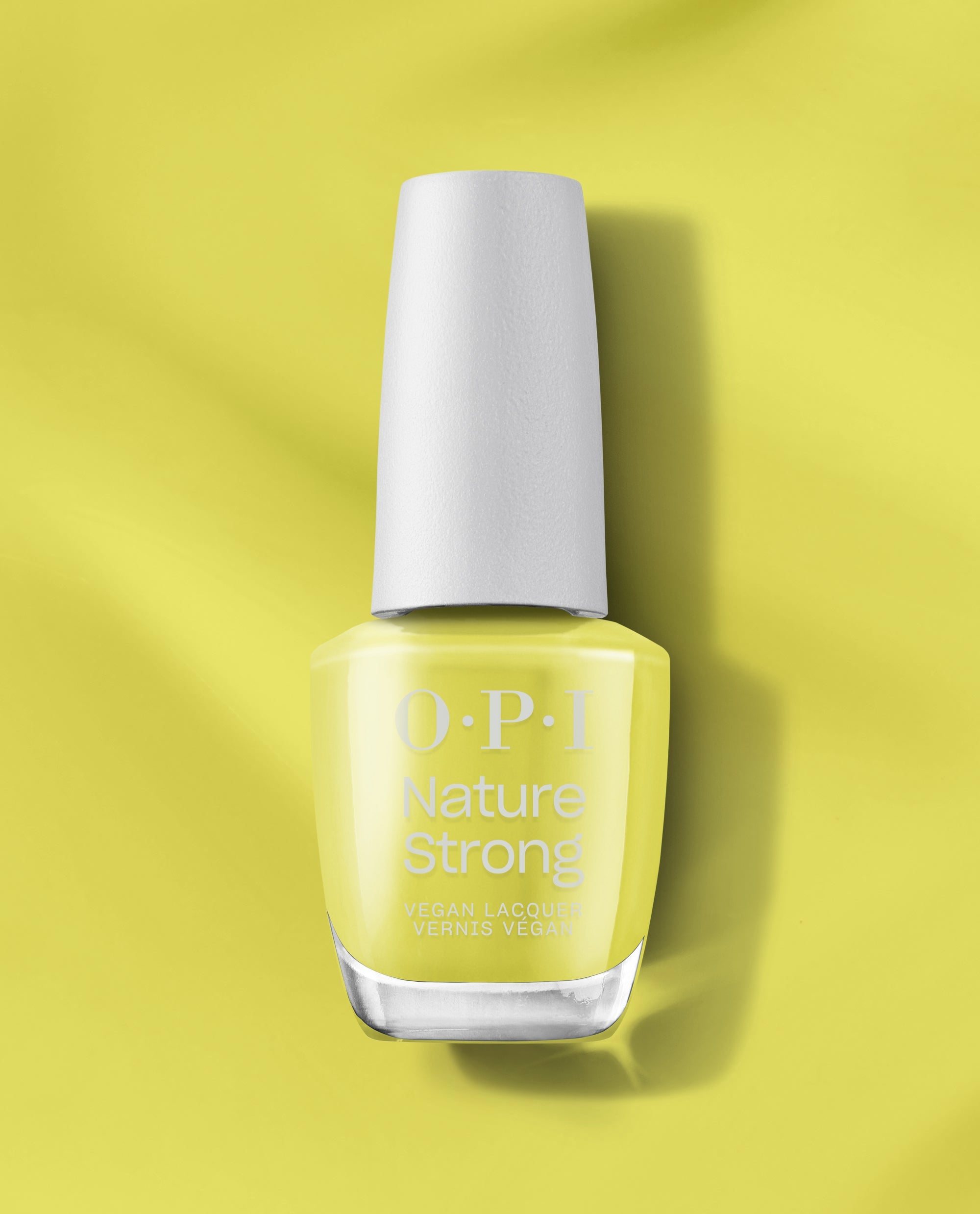 OPI Nature Strong Vegan Nail Lacquer in Give Me Some Suga Cane standing upright, white cap and clear bottle revealing a pale lime-green hue, casting a soft shadow on a matching glossy background—green nail polish ideal for spring nail colors.