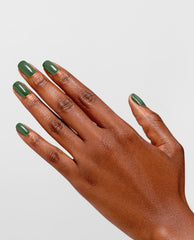Hand with glossy evergreen manicure showcases OPI Infinite Shine Happily Evergreen After green nail polish on rounded nails, fingers splayed against a clean light gray background, highlighting a fresh pick for spring nail colors.