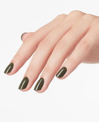 Manicured hand showcases glossy deep olive green nail polish—OPI Suzi - The First Lady of Nails nail lacquer—on almond-shaped nails against a clean white background, highlighting green nail polish trends and versatile spring nail colors.